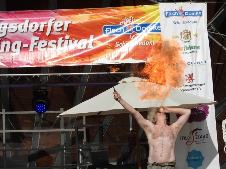 Performer erzeugt eine große Flamme vor der Bühne des Heringsdorfer Bodypainting Festivals